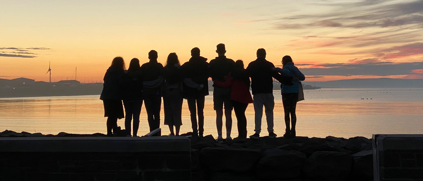 Students embracing while looking at the sunset