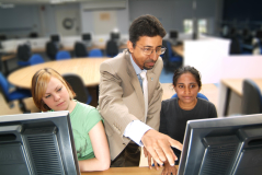 A male tutor aiding students with computer studies