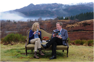 A photograph of Jenni Steele, Head of Partnership Communications at VisitScotland and Professor Alan Riach, Professor of Scottish Literature, sitting on a sofa in the Scottish landscape, holding books and talking. 