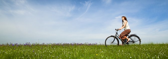 girl riding bike through sunny meadow