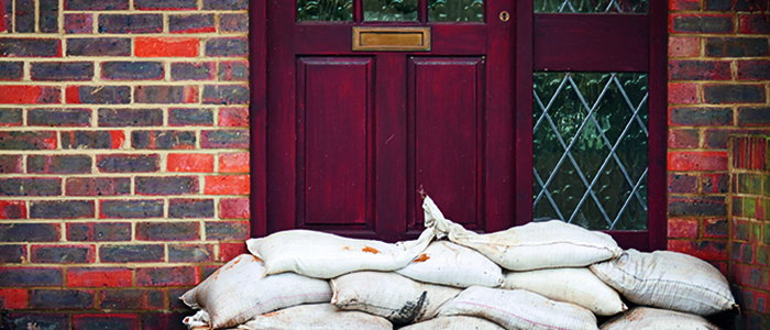 Flooded street with sandbags at door.