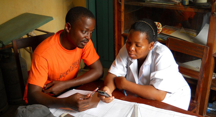 Zac Mtema training a healthworker to use mobile app. Credit Katie Hampson