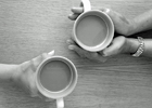 Two people's hands holding mugs of tea