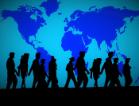 People walking, silhouetted in front of a world map