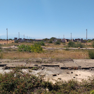 A photograph of a dry landscape with electricity pylons and houses. 