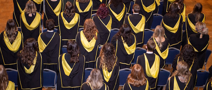Students standing next to their seats in Bute Hall during graduation