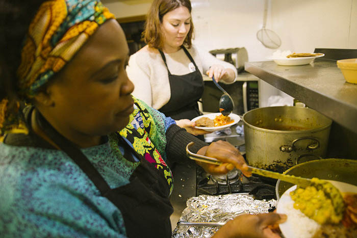 Two women plating up food in a kitchen at one of the 2017 Africa in Motion dine and view events
