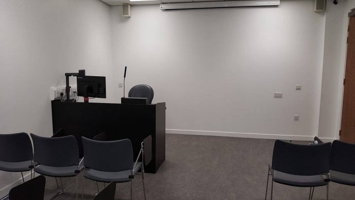 Flat floored teaching room with rows of tablet chairs, screen, visualiser, and PC