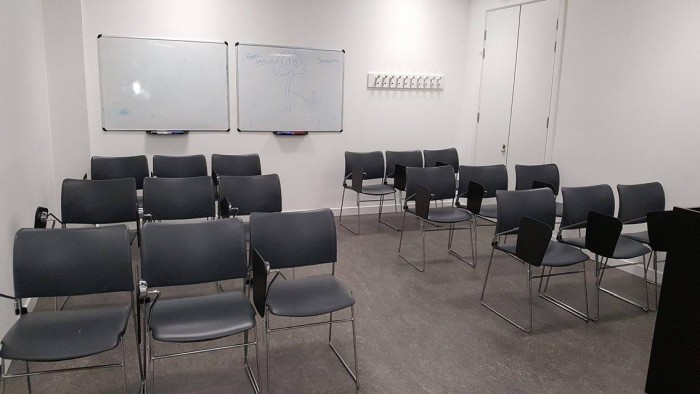 Flat floored teaching room with rows of tablet chairs and whiteboards