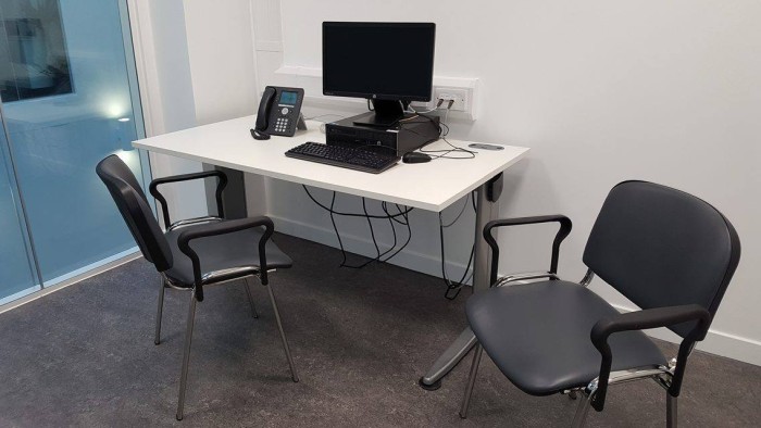 Flat floored interview room with chairs and desk with PC and telephone