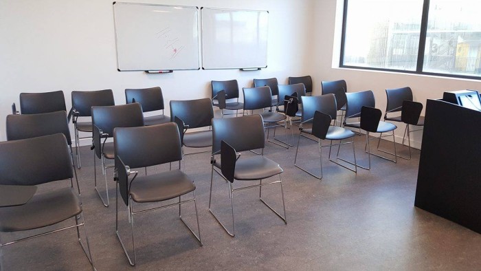 Flat floored teaching room with rows of tablet chairs and whiteboards
