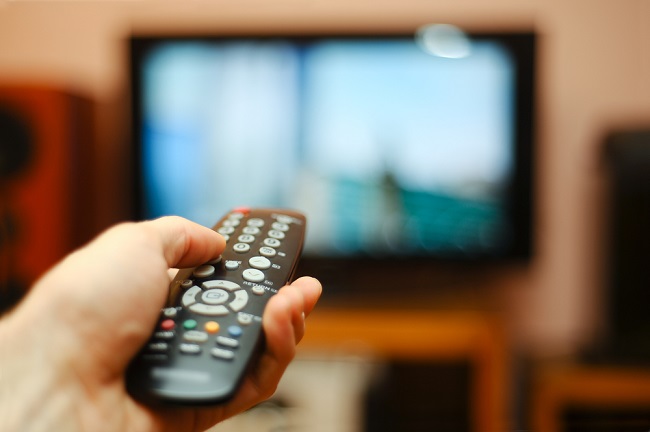 A person holding the remote in front of the TV