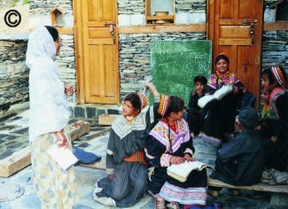 Dr Azra Meadows teaching Kalash girls in the valled of Rumbur, Chitral, NWFP, Pakistan, 2005.  Rural education, especially of girls, is of paramount importance in isolated communities.  The girls are dressed in traditional Kalash costumes