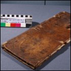 This photograph shows a three-quarter view of the front cover with significant damage caused by handling and changes in temperature and humidity before conservation treatment. (GUAS Ref: UGC 182. Copyright reserved.)