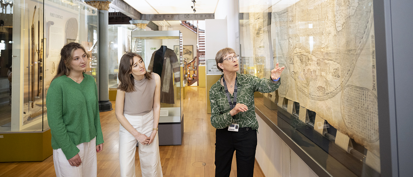 A museum tour guide pointing out details on an old world map