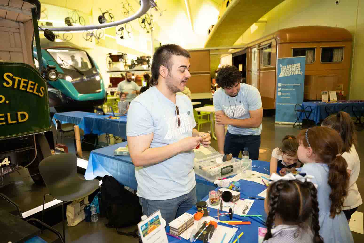 Photograph showing 2 GSF in Action students in the Riverside Museum helping a group of school children. 