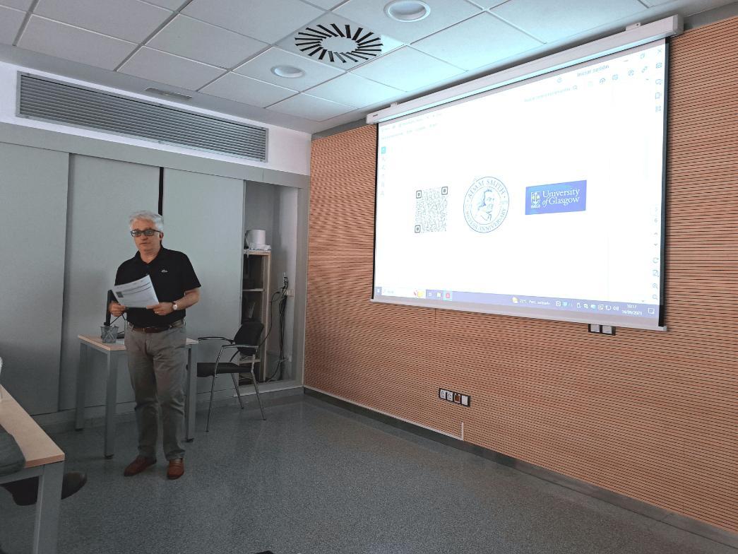 Eugenio Porto standing speaking to an audience. With a presentation behind him. 