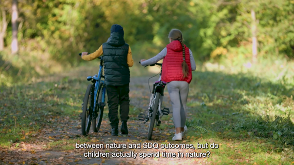 A rearview of 2 children walking their bikes along a country path