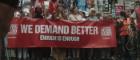 People at the front of protest march carrying a banner which reads ' We Demand Better. Enough is Enough'