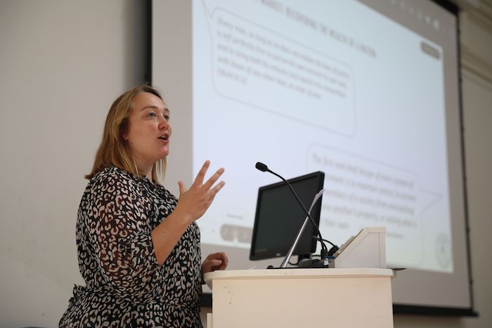 Professor Kat Riach speaking at a podium