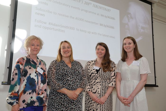 Professor Kat Riach and other representatives in front of a presentation