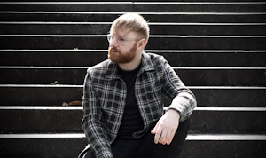 A man sitting on a set of steps outside, looking off camera