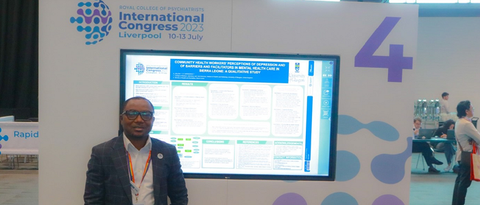 Photo of Abdul Jalloh standing next to a poster of his research findings