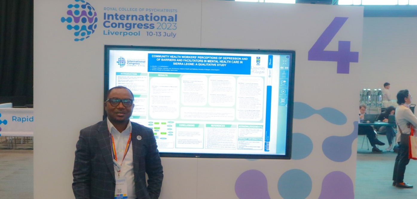 Photo of Abdul Jalloh standing next to a poster of his research findings