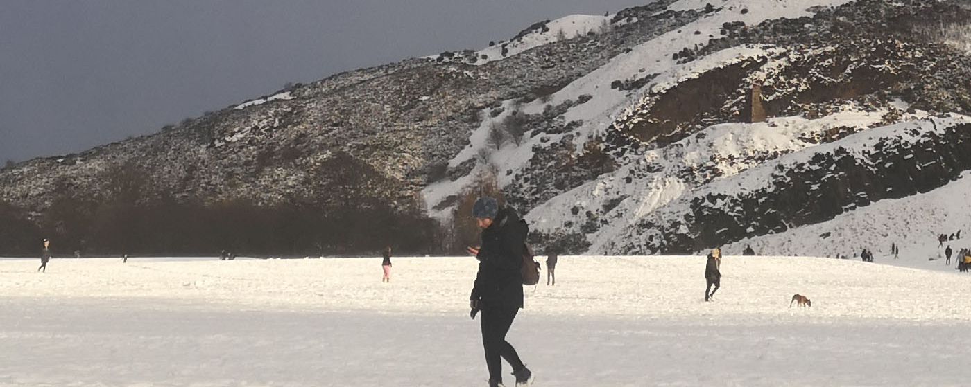 photo of people walking in snow under grey sky