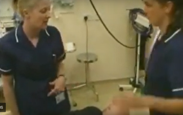 Two nurses at a patient's bedside discussing his condition