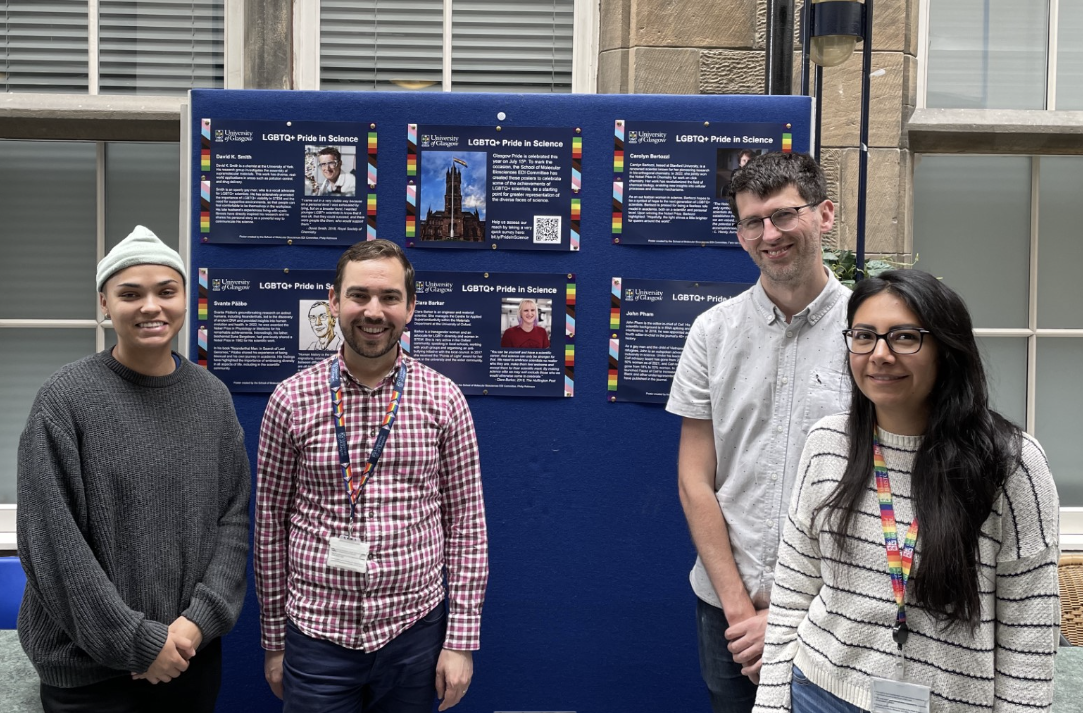 SMB Members in front of boards displaying posters of LGBTQIA+ scientists