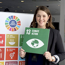 Student standing in front of poster for sustainable development goals