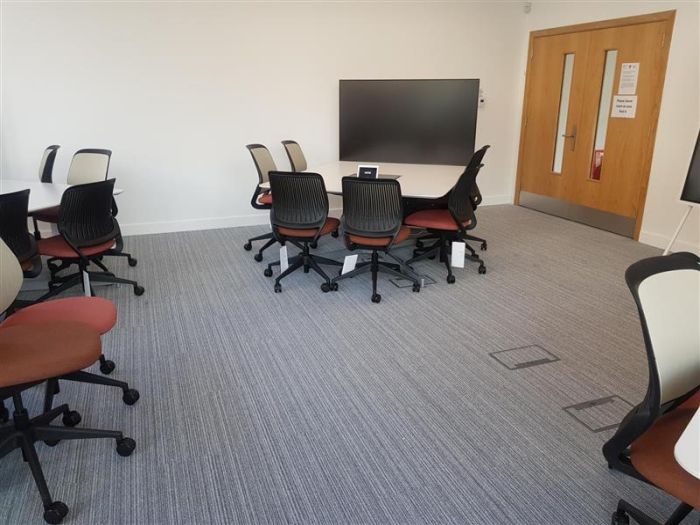 Flat floored Tech Enabled Active Learning (TEAL) room with groups of tables and chairs, each with a video monitor.