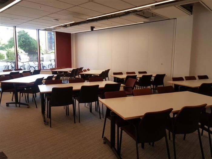 Flat floored teaching room with tables and chairs in groups.