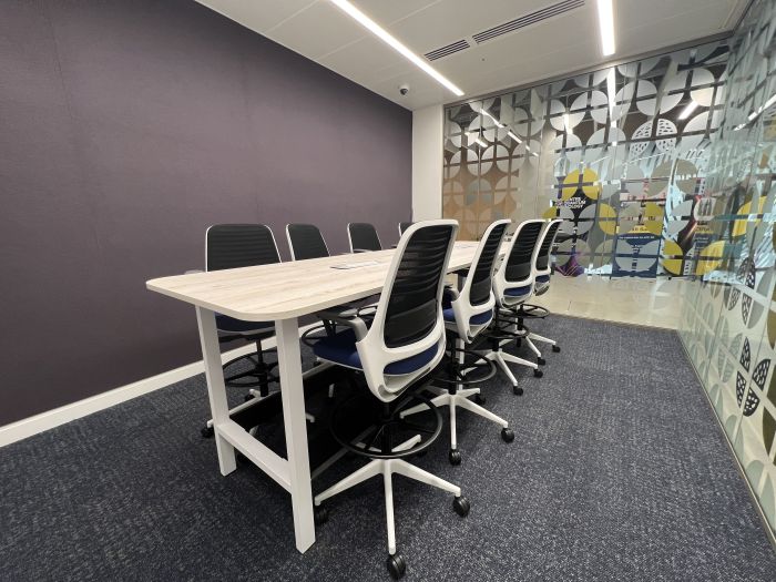 Flat-floored meeting room with high boardroom table and chairs.