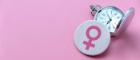 A button with the gender symbol for women - a circle above a cross - next to an old fashioned handheld timepiece on a pink background. Source: Adam Smith Business School https://www.gla.ac.uk/schools/business/research/centres/hrm/impact/ammino/