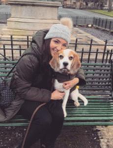 Image of Rachel Hume crouching and holding a white and tan dog