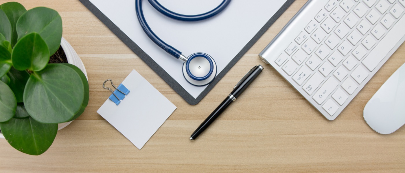 Photo of a table with pen, keyboard, plant and stethoscope