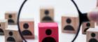 Wooden blocks with abstract image of person scattered centre a magnifying glass is held over one block coloured red 