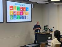 Man standing in front of presentation screen giving a lecture