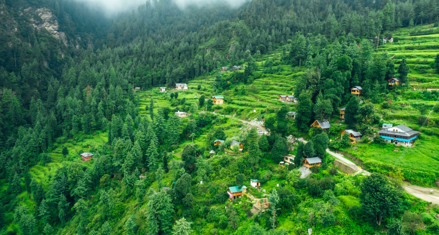 aerial landscape of local homes in the mountain village and hill station of Jibhi surrounded by greenery and cedar forest [Photo: Shutterstock]