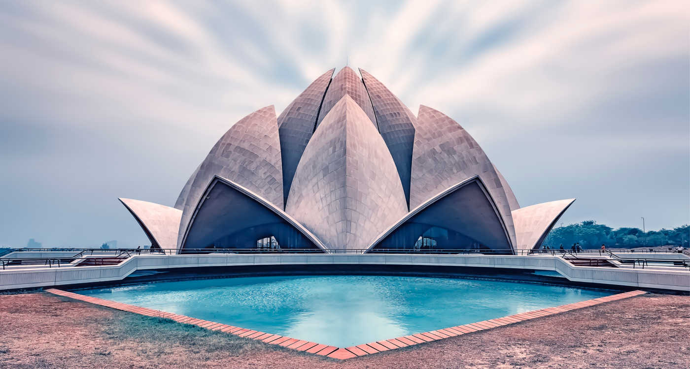 Outside of the Lotus Temple which is shaped like a flower, with a blue water pool in front [Photo: Shutterstock]
