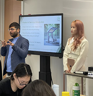 Two students giving a presentation in front of a screen
