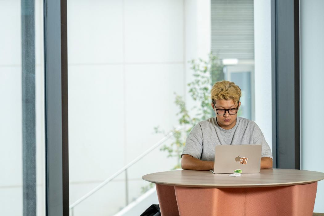 A student sitting at a desk in the ASBS PG learning hub, studying on a laptop