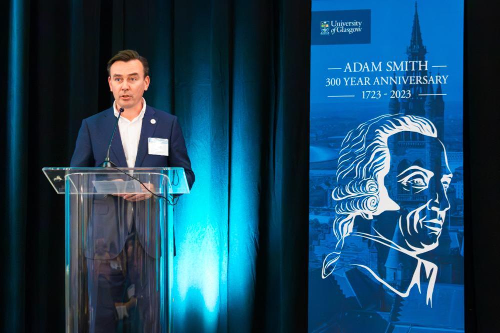 Craig Smith standing at a podium with an Adam Smith banner behind him Source: Amy Laux