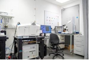 Lab bench with Lightsheet imaging equipment and monitors. Whiteboards on wall behind. 