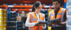 A man and a woman working in a warehouse holding ipads