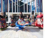 Photo of some people dancing wearing colourful outfits in the University of Glasgow's St Mungo Square