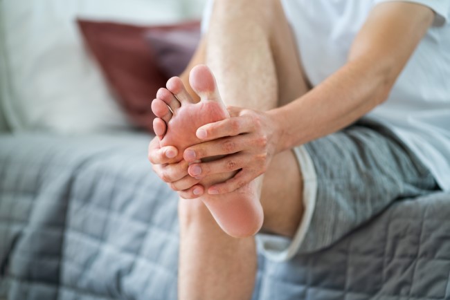 Image of man, holding his foot, in pain with gout