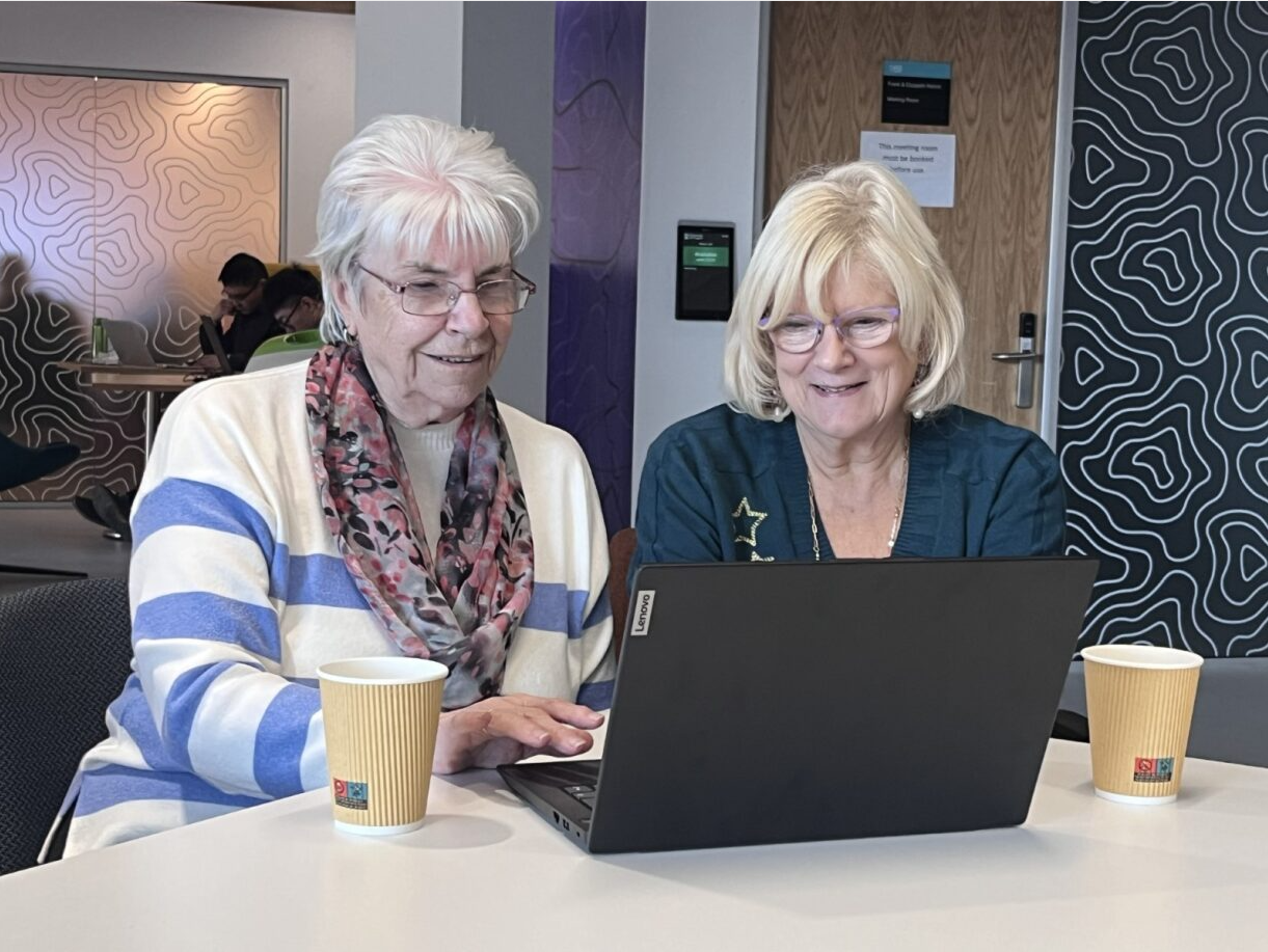 Two women sitting at a laptop at a ALISS Community Drop In